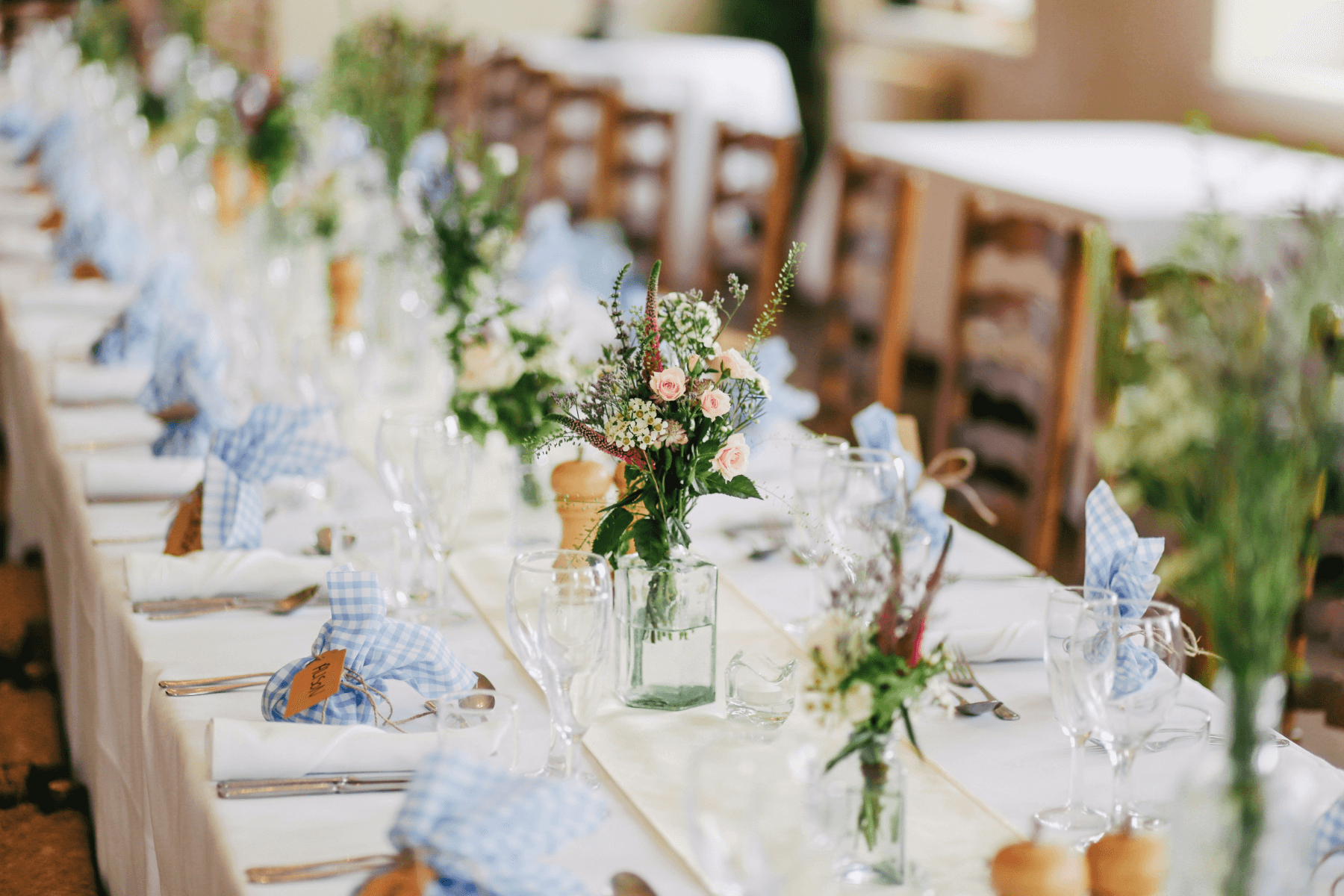 A table set with a white tablecloth, flowers, silverware, and wine glasses.