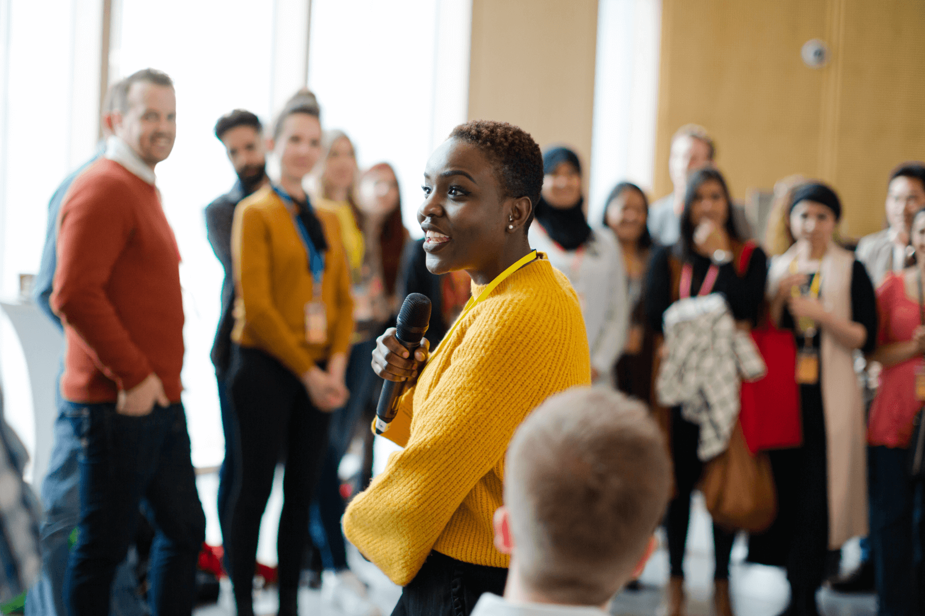 A woman speaking into a microphone to guests at an event.