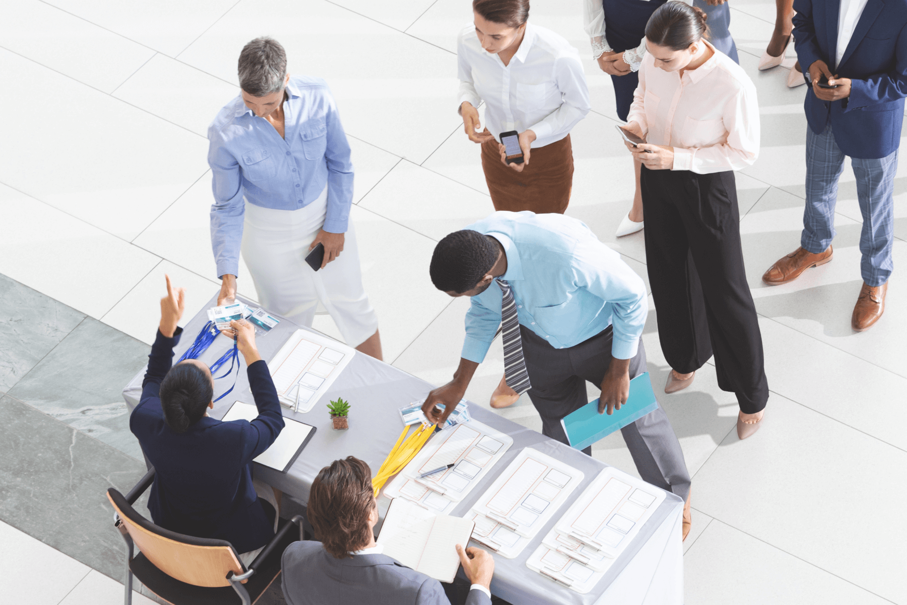 A group of people in business attire are lined up at a table to sign in for an event.