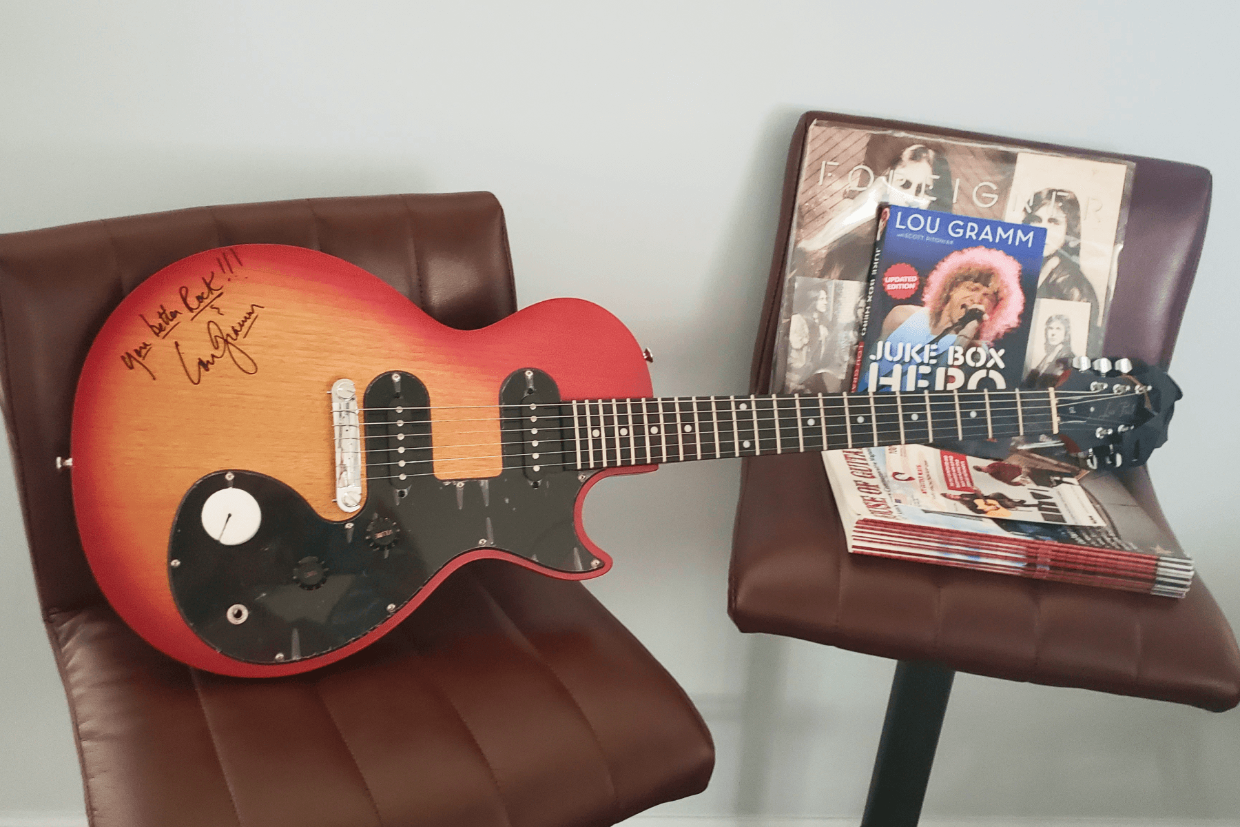 An autographed guitar, a Foreigner record, and a book by Lou Gramm.