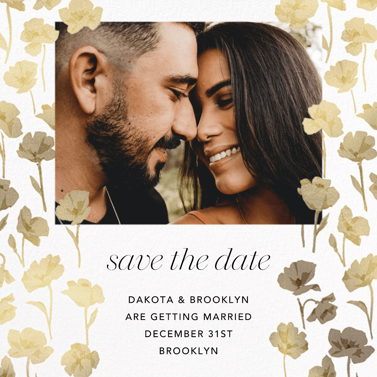 A save the date featuring a photo of a couple surrounded by gold flowers in front of an envelope with matching gold flowers on the lining.