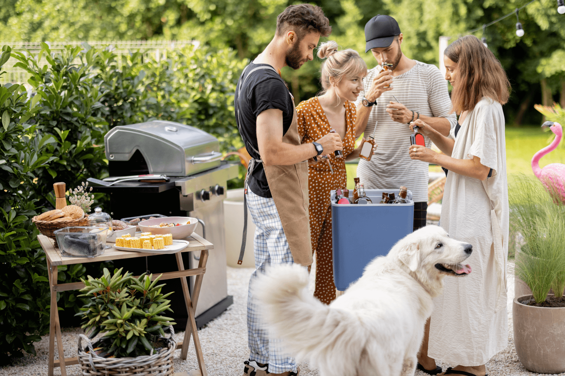 Two men, two women, and a dog are in a backyard with a grill and bottles of alcohol.