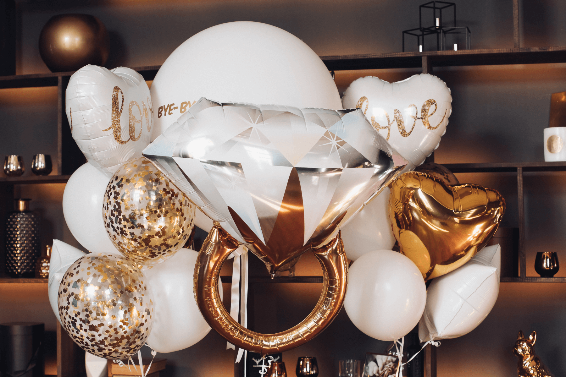 White and gold balloons and an engagement ring-shaped balloon.