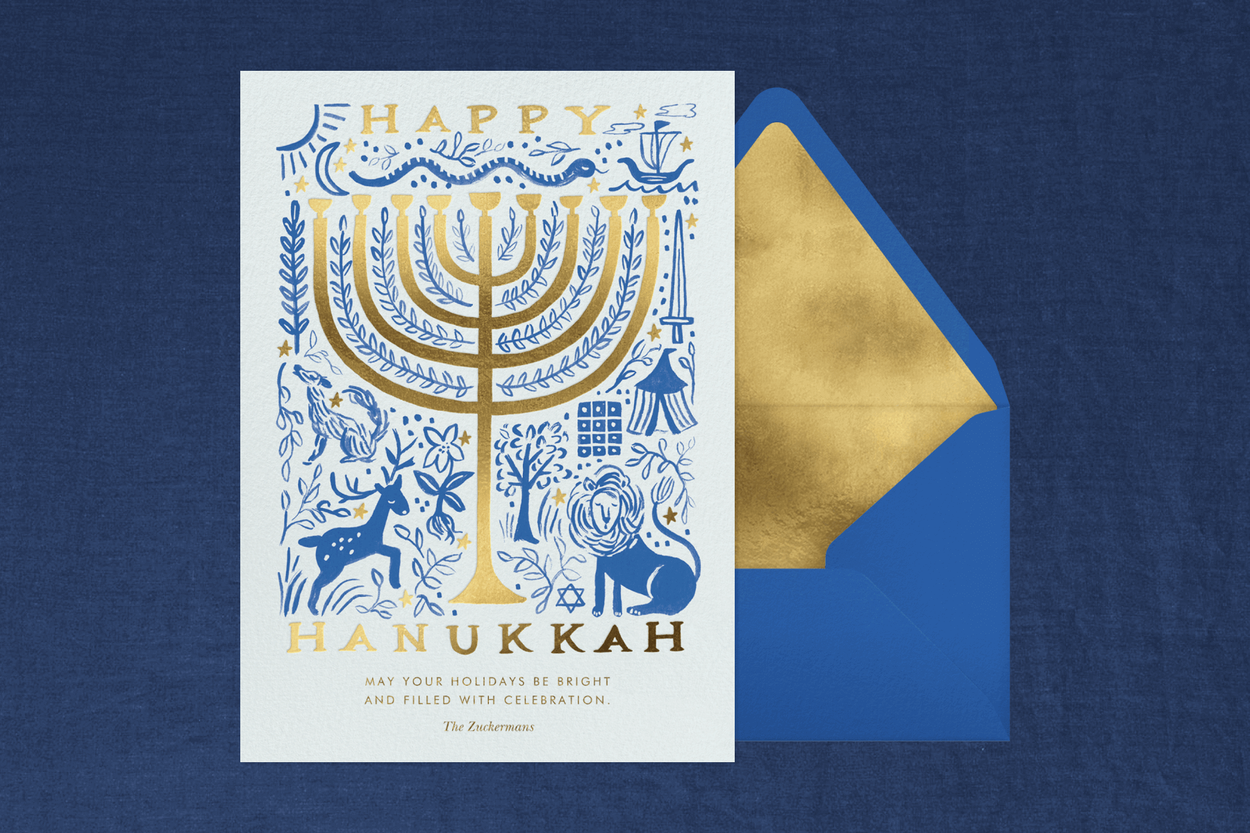 A Hanukkah card with a menorah and illustrations in front of a blue and gold envelope. 