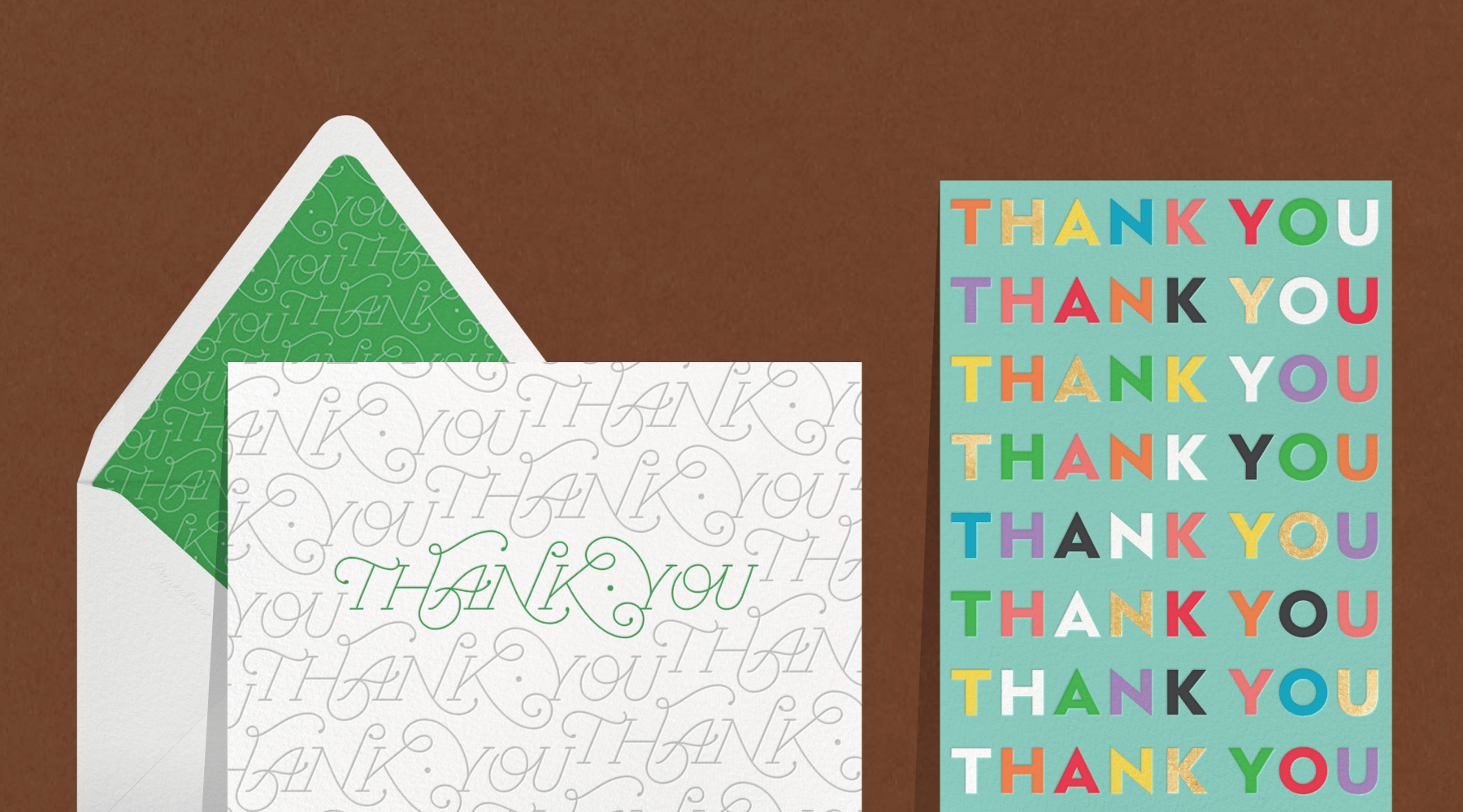 A card reads THANK YOU repeatedly in gray and green script font with a white and green envelope; a robin’s egg blue card reads THANK YOU several times in rainbow block letters.