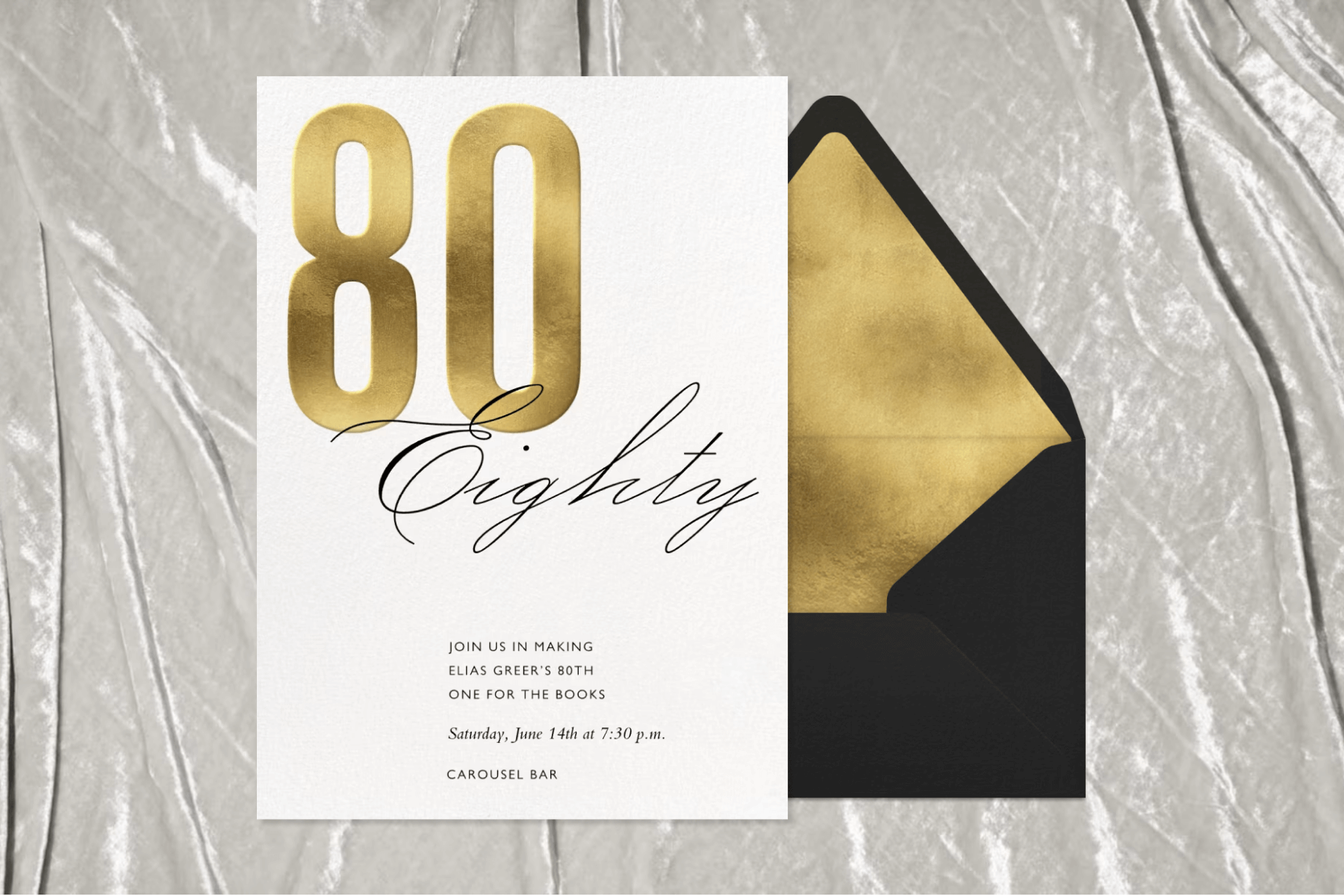 A white invitation with a large gold metallic ‘80’ and cursive black text reading ‘EIGHTY’ over a silver fabric-style backdrop.