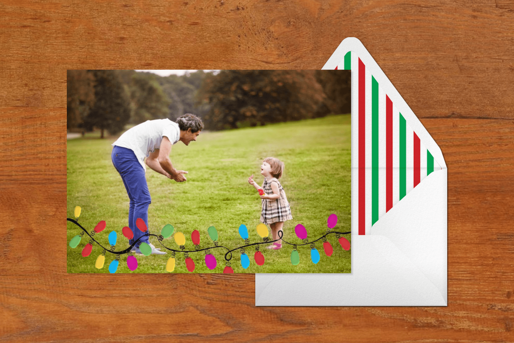 A card with a string of Christmas lights featuring a photo of a father playing with his child. 