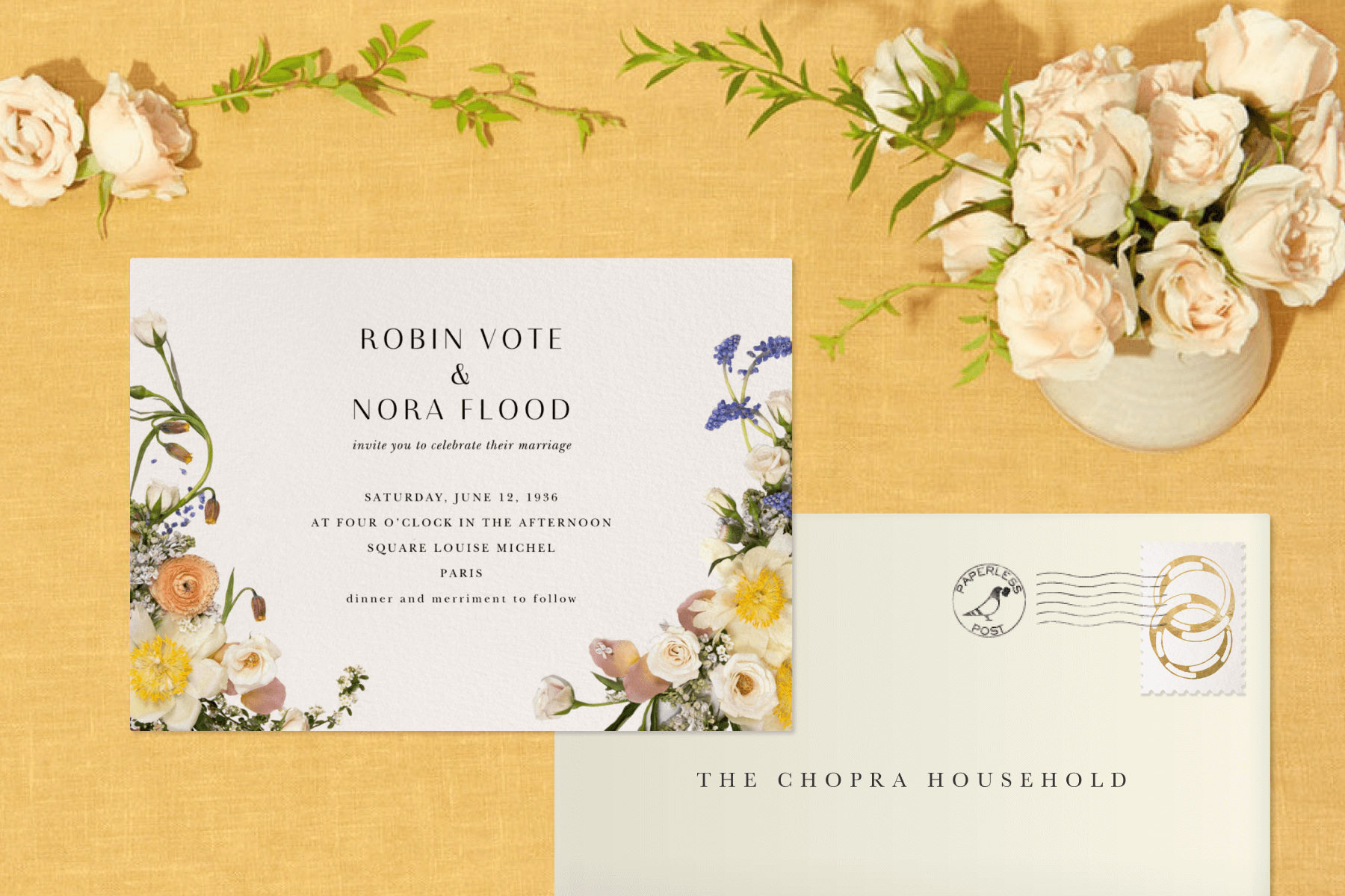 A floral wedding invitation and envelope over a yellow background with a vase of roses. 