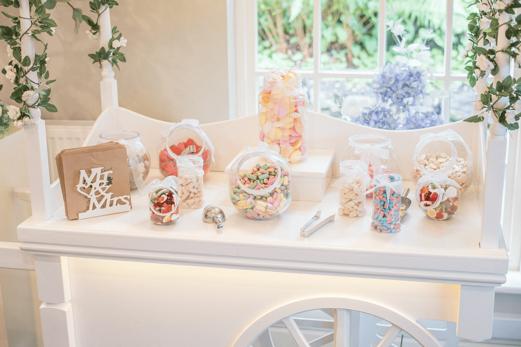 A white table set with jars of various candies.