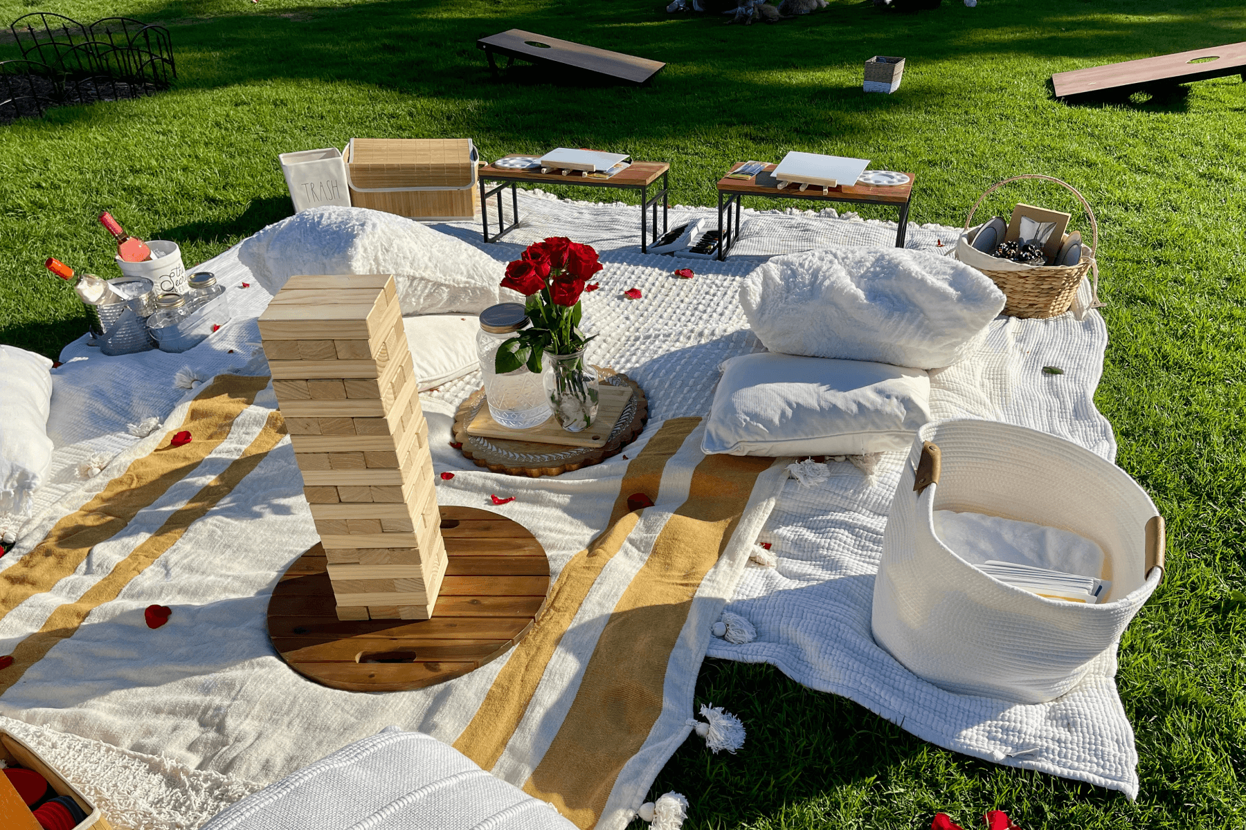 An outdoor picnic setup with pillows, blankets, and a game of Jenga.