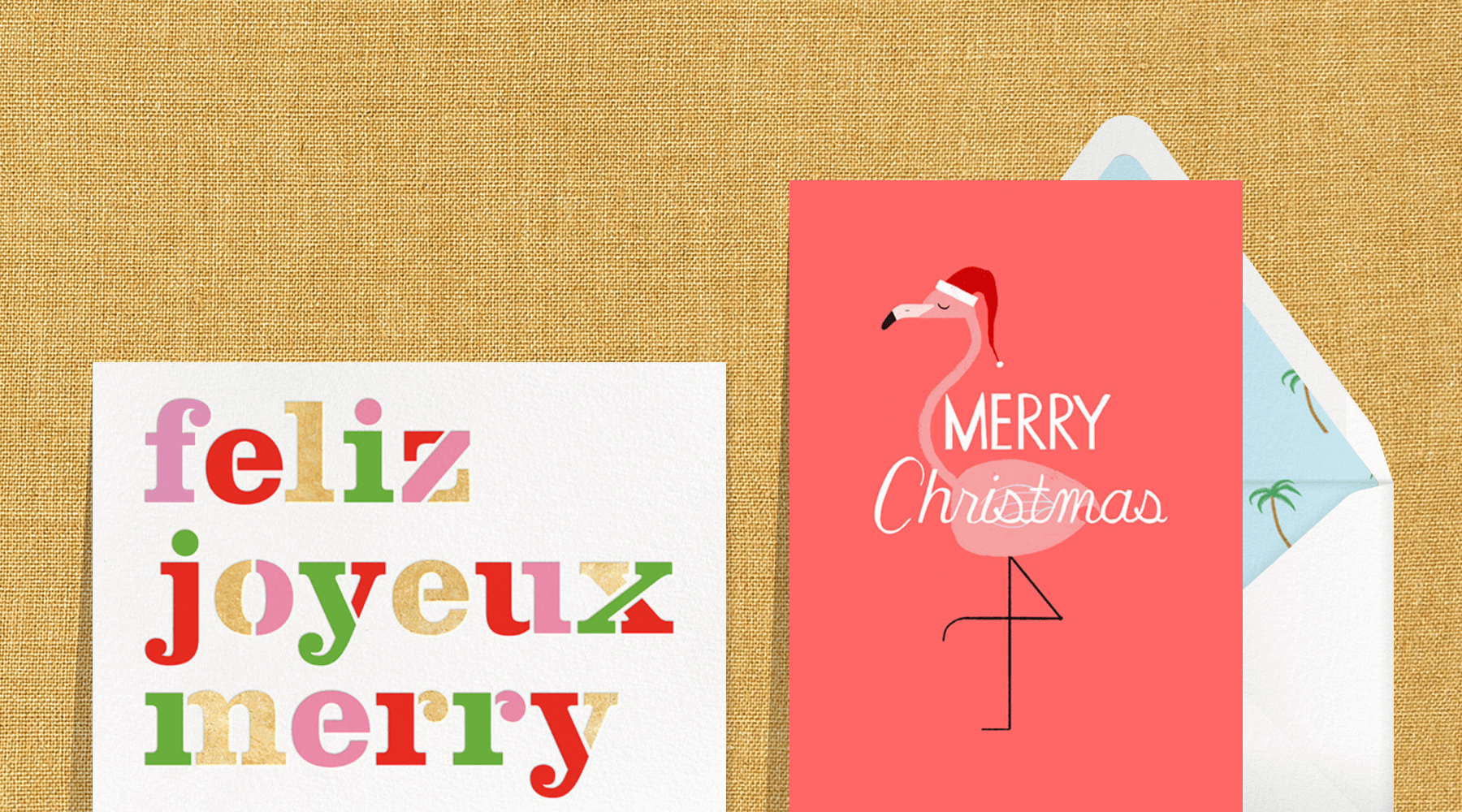 A card reading feliz, joyeuz, merry in pink, red green and gold next to a red card with a flamingo in a santa hat