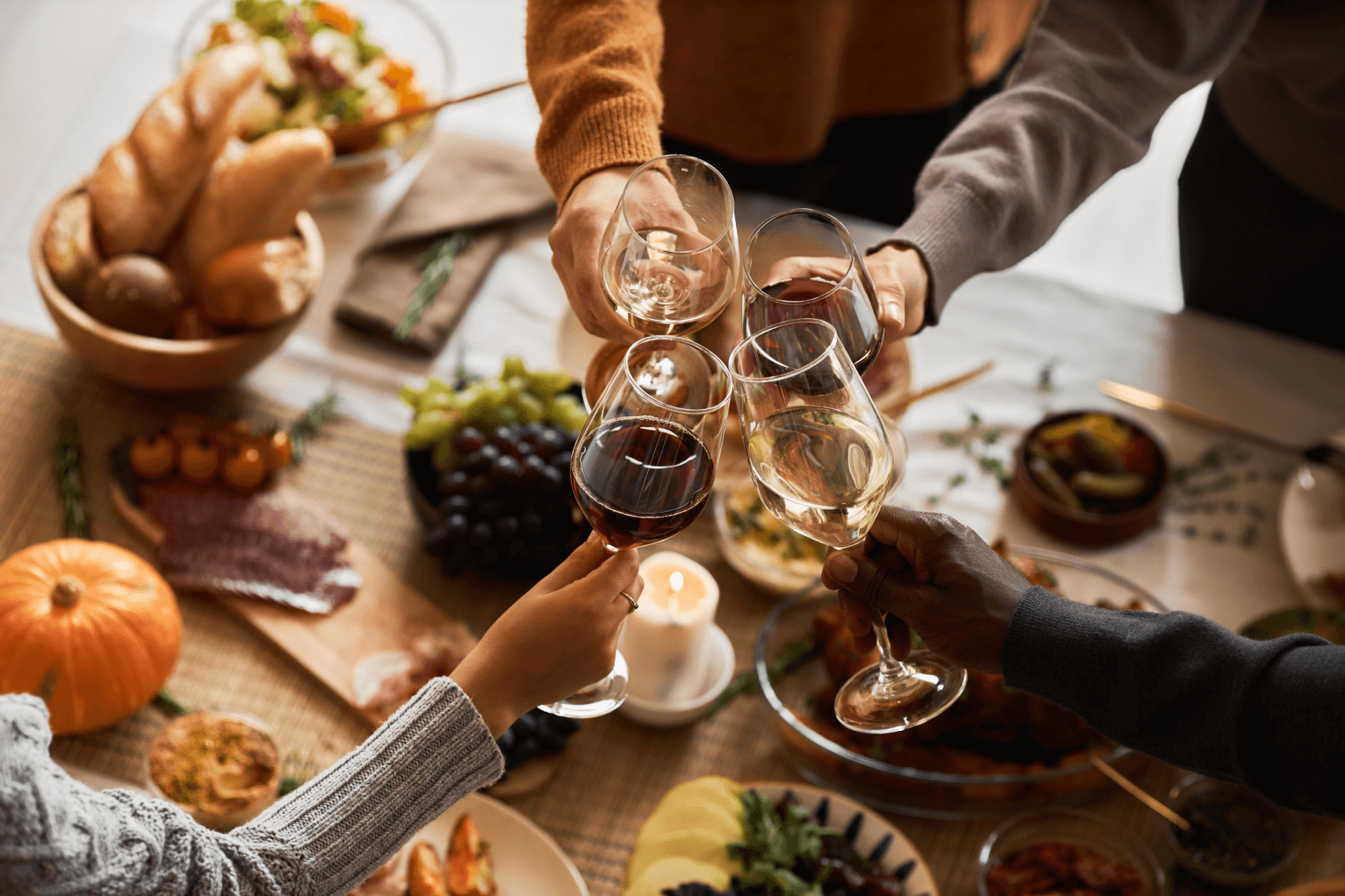 Five friends clicking glasses of wine in a beautiful fall vineyard setting.