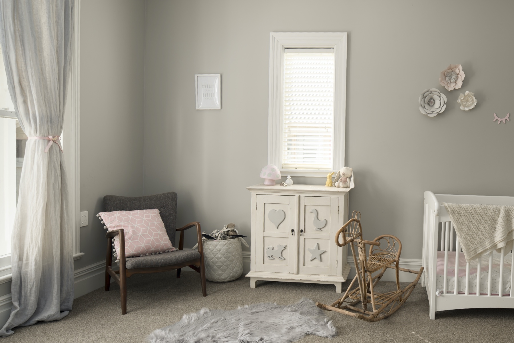 Photo of a nursery featuring a chair, changing table, and rocking horse.